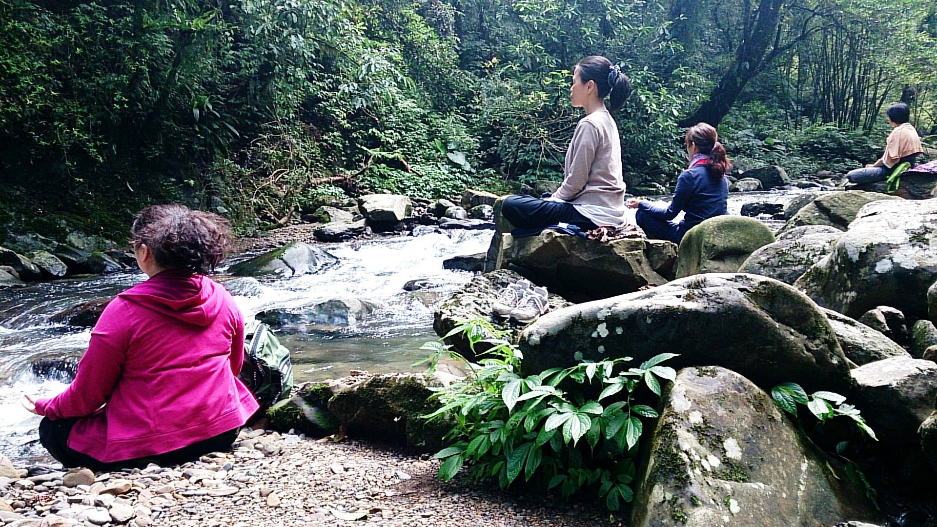 Women meditating beside a stream in Taiwan